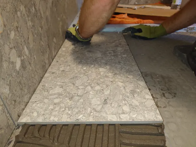 Large format porcelain floor tile being bedded onto combed adhesive